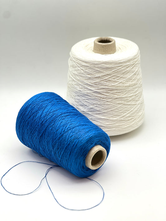 Two spools of thread, one blue and one white, on a light gray background.