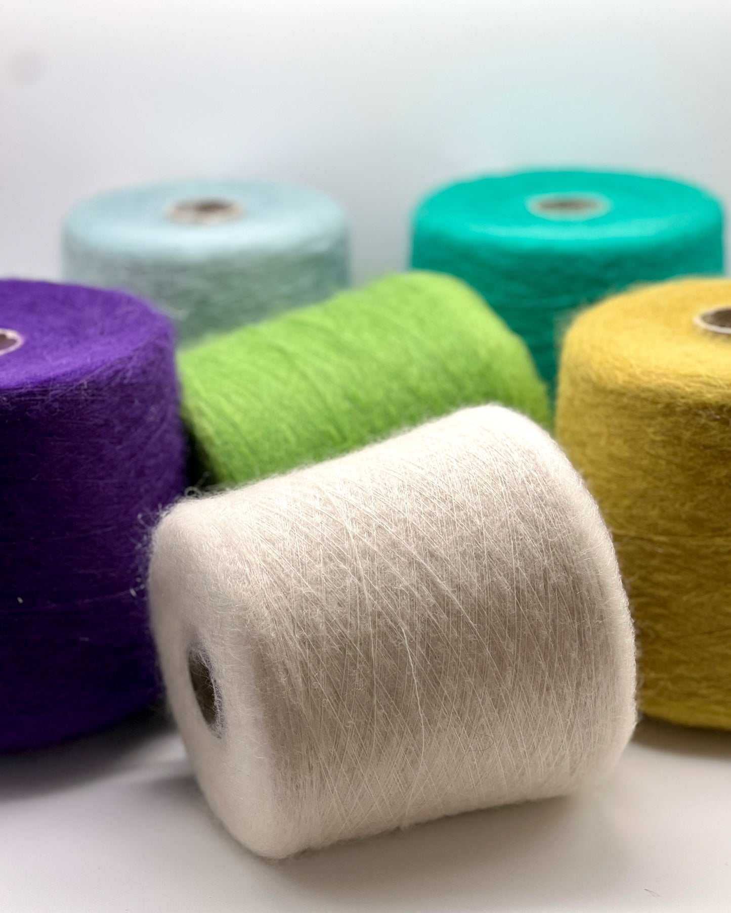 Assorted spools of yarn in various colors on a white background