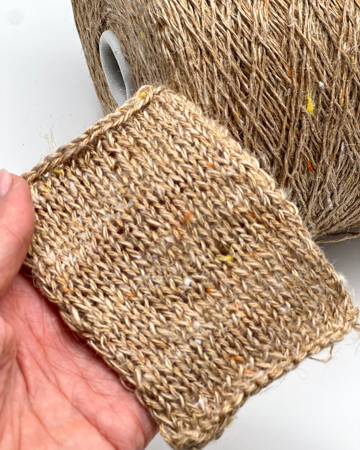 Close-up of a hand holding a piece of textured brown fabric against a white background