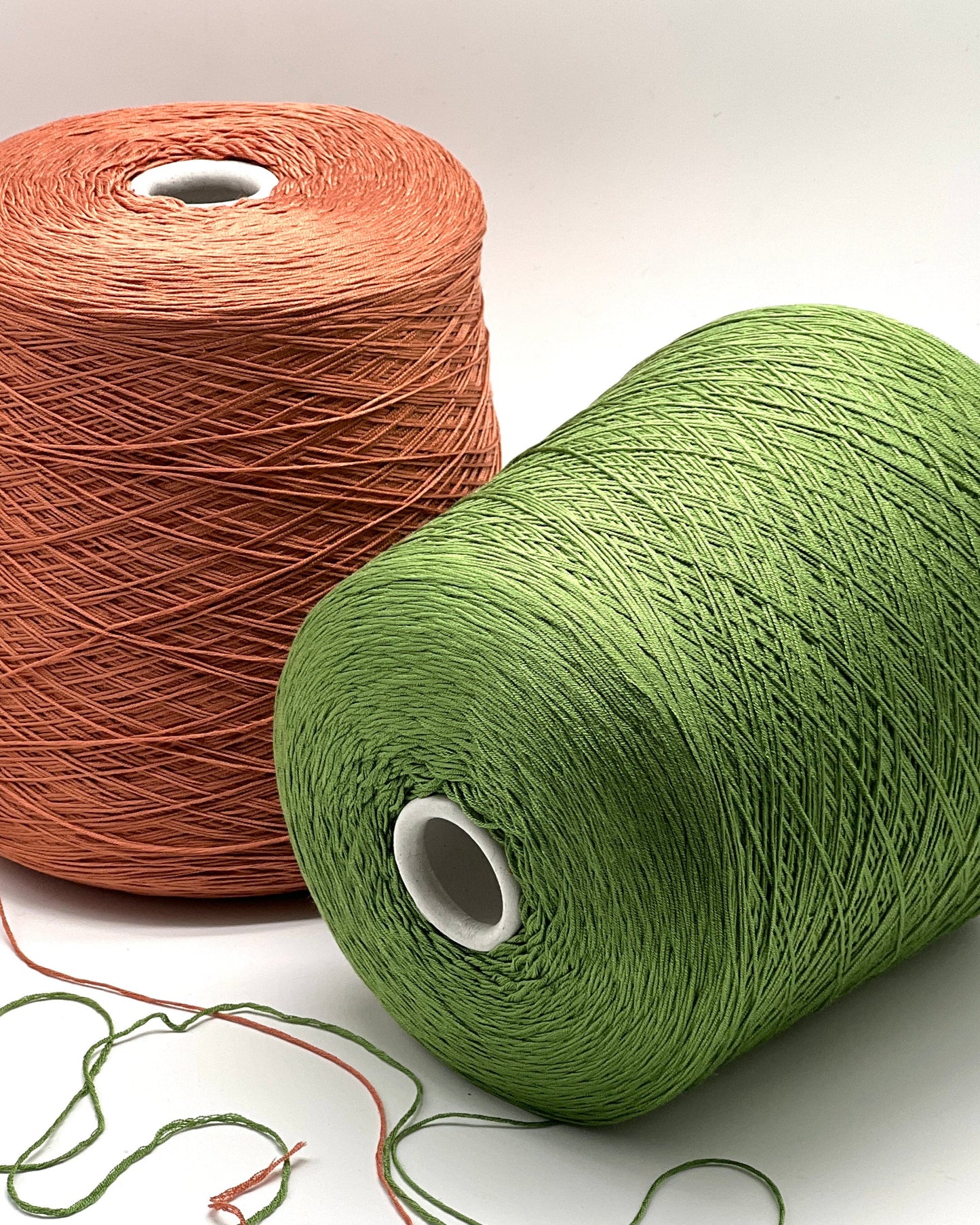 Two spools of yarn, one brown and one green, on a white background.
