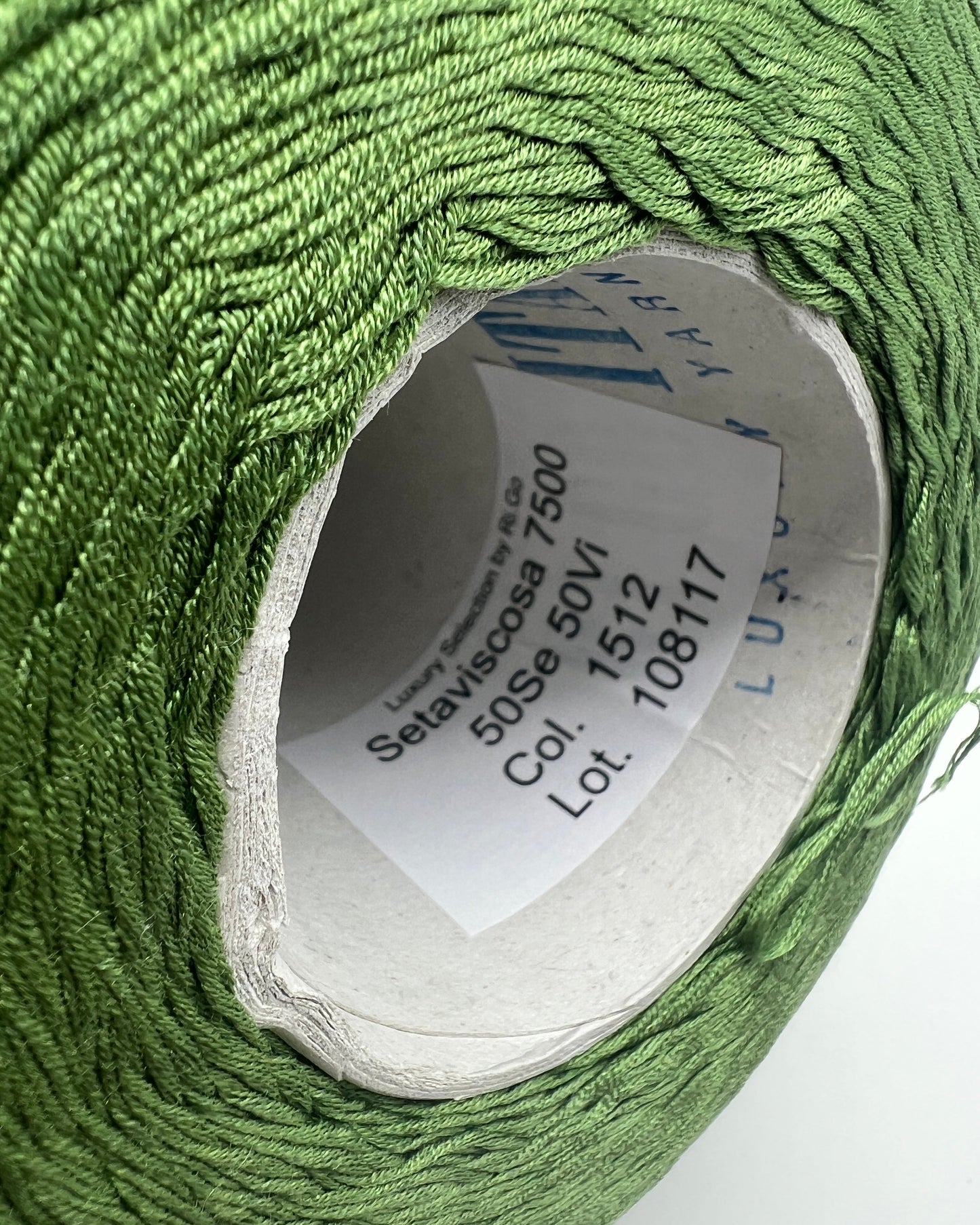 Close-up of a spool of green thread with a label on a white background