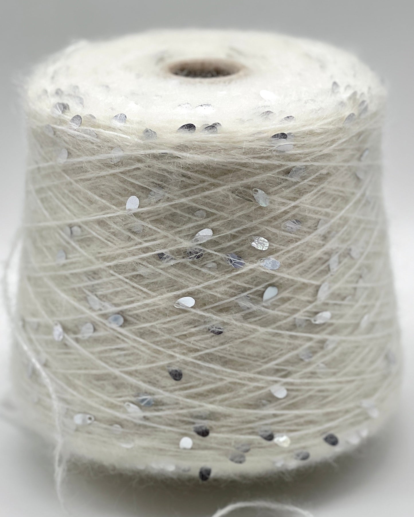Spool of white thread with small black and gray dots on a light gray background