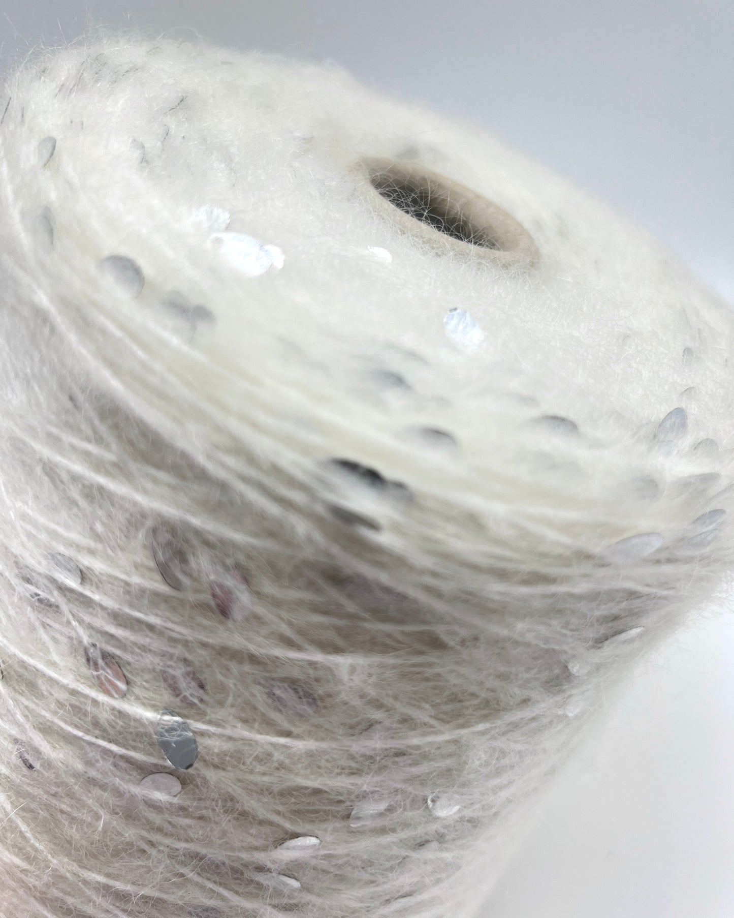Close-up of a spool of white thread with small black dots on a white background