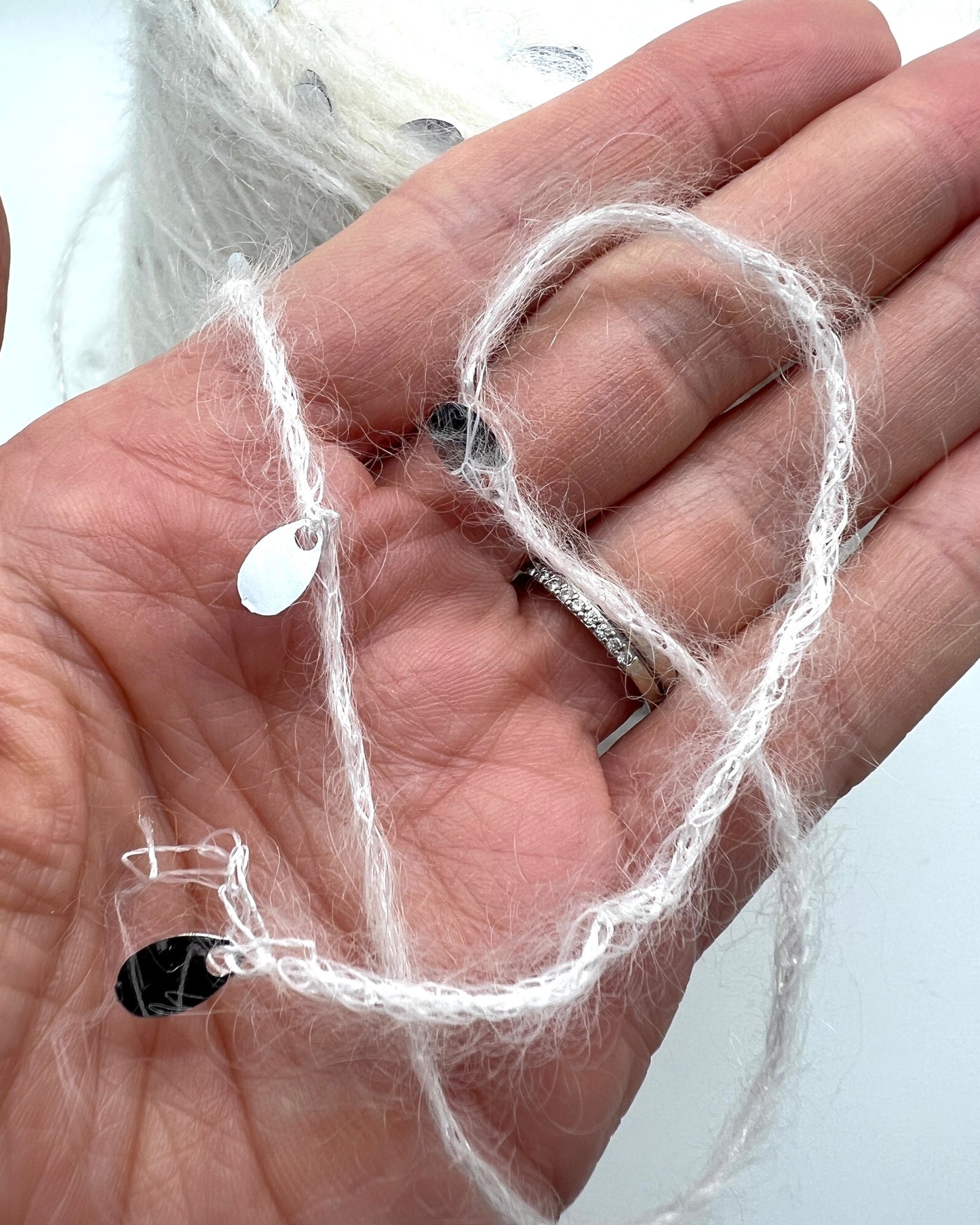 Hand holding a small heart-shaped object with white string