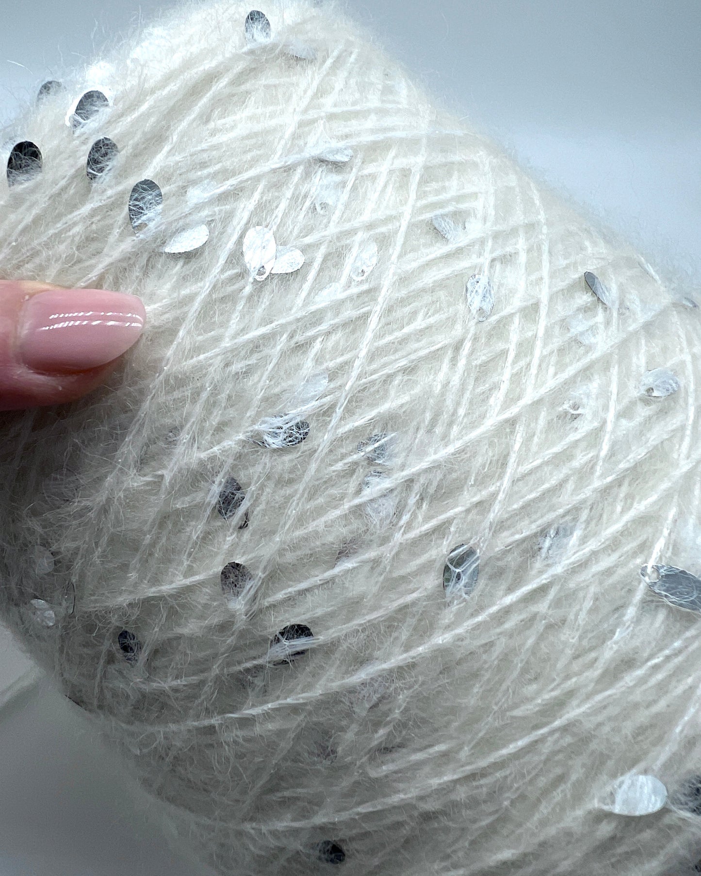 Close-up of a textured white fabric with small black beads, held by a hand.