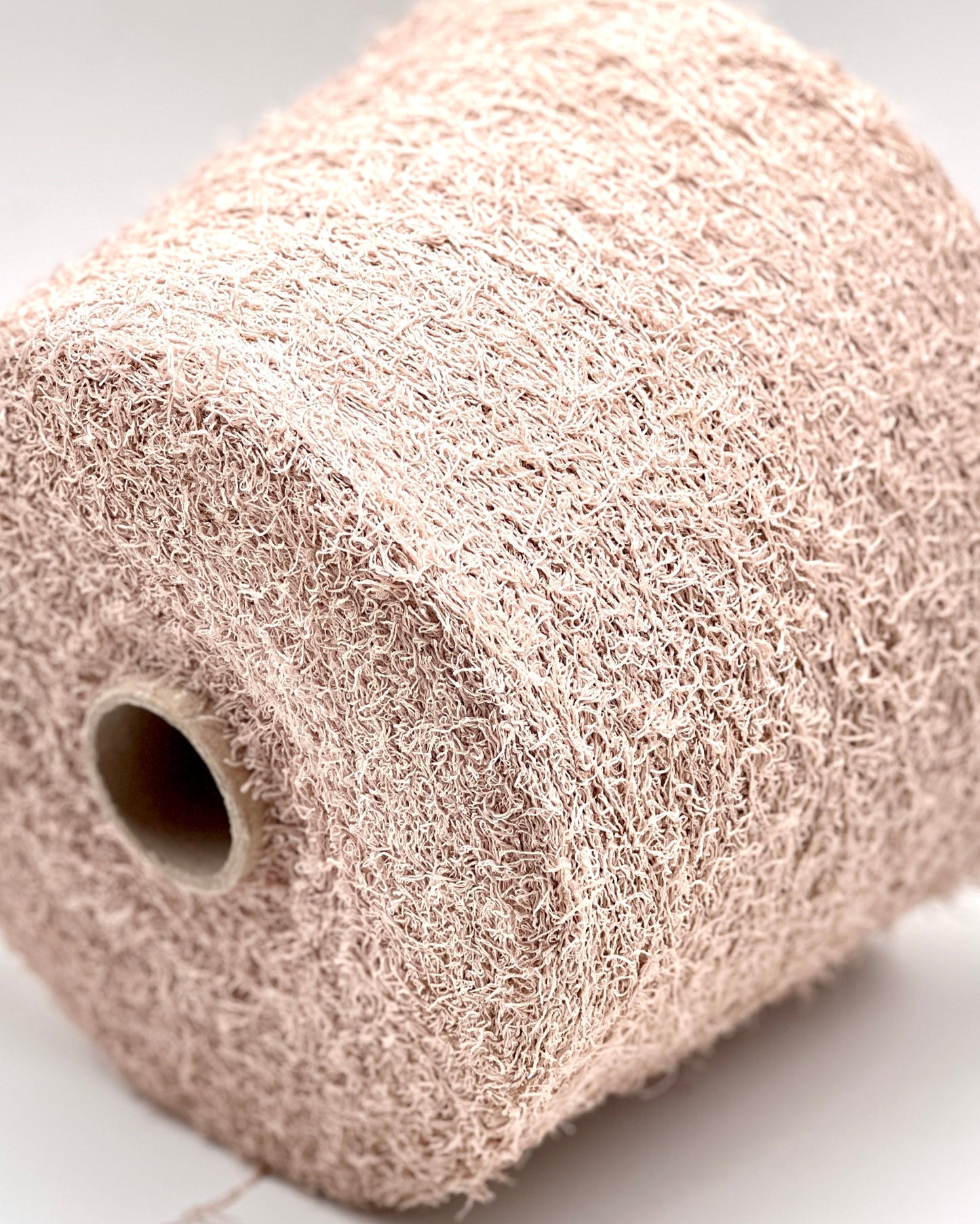 Close-up of a roll of beige knitted fabric on a light background