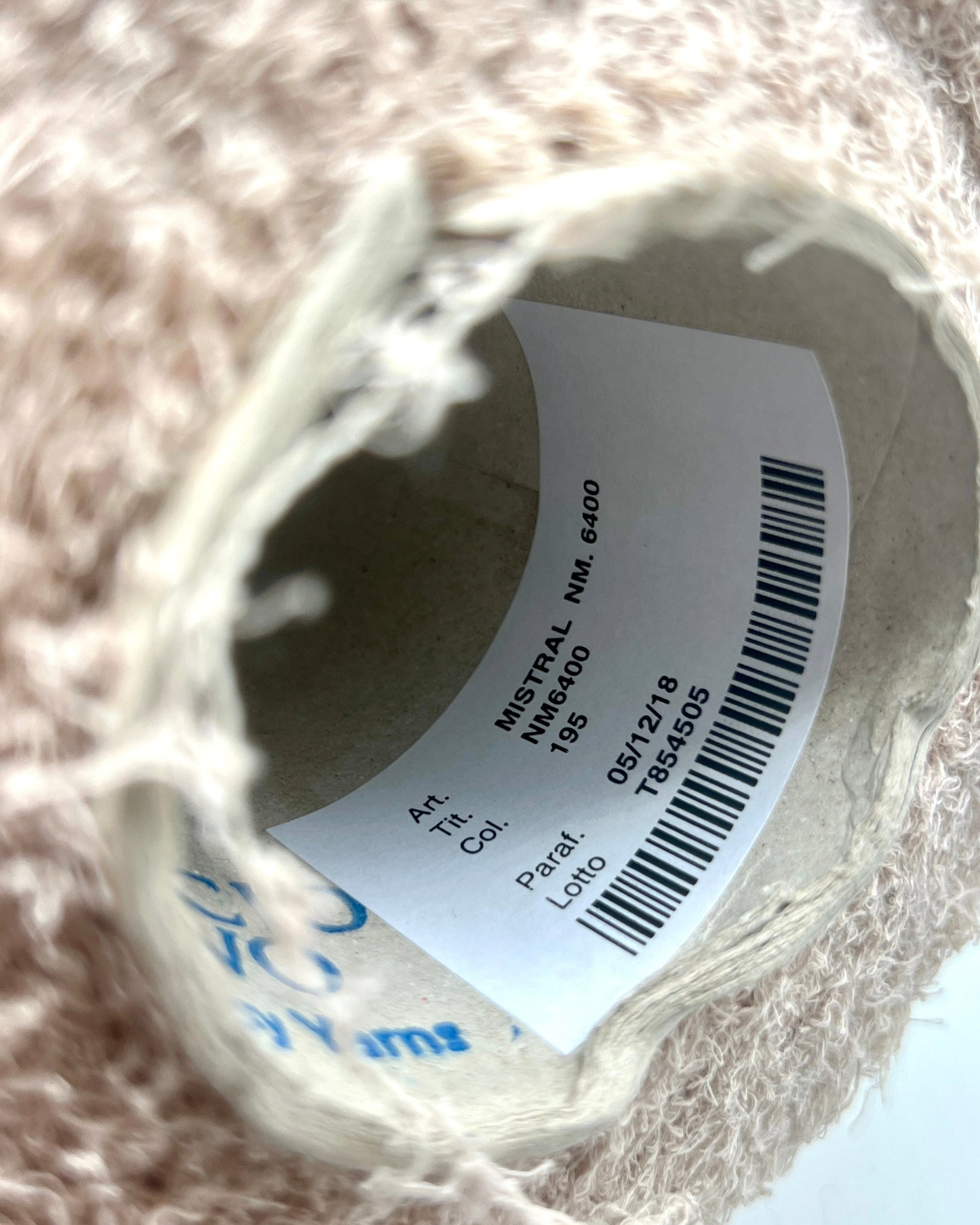 Close-up of a spool of thread with a label on a textured surface