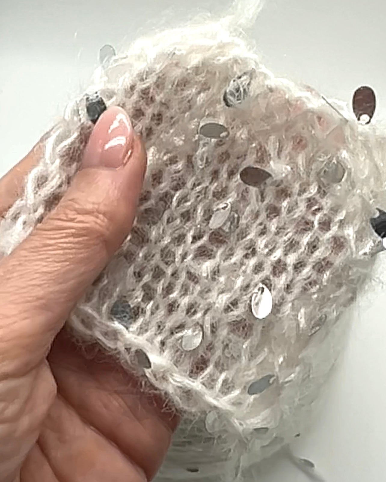 Hand holding a piece of white fabric with black patterns on a white background