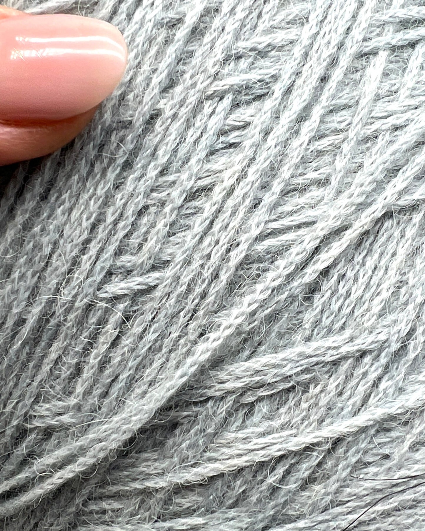 Close-up of gray yarn with a hand holding it