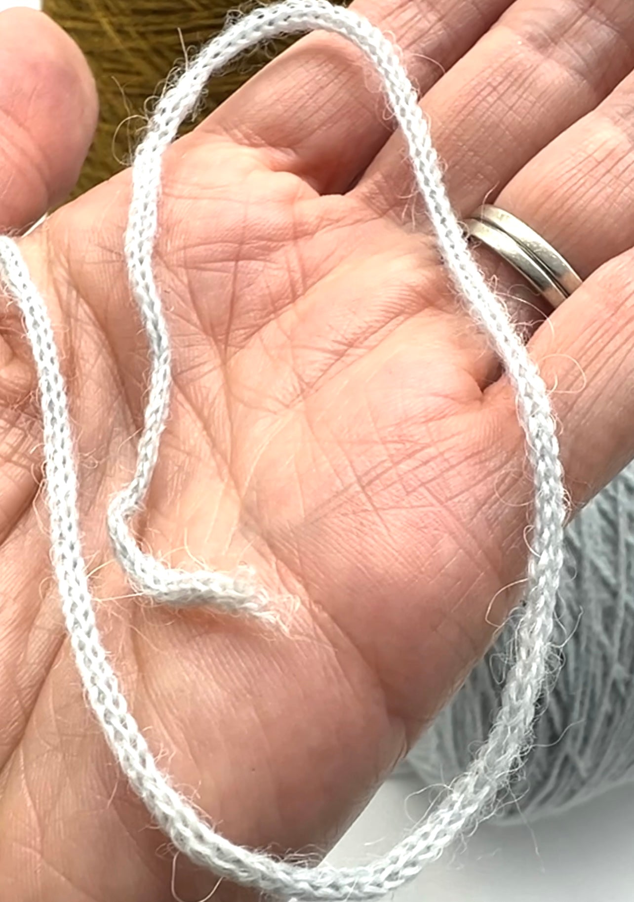White string held in a hand with a blurred background