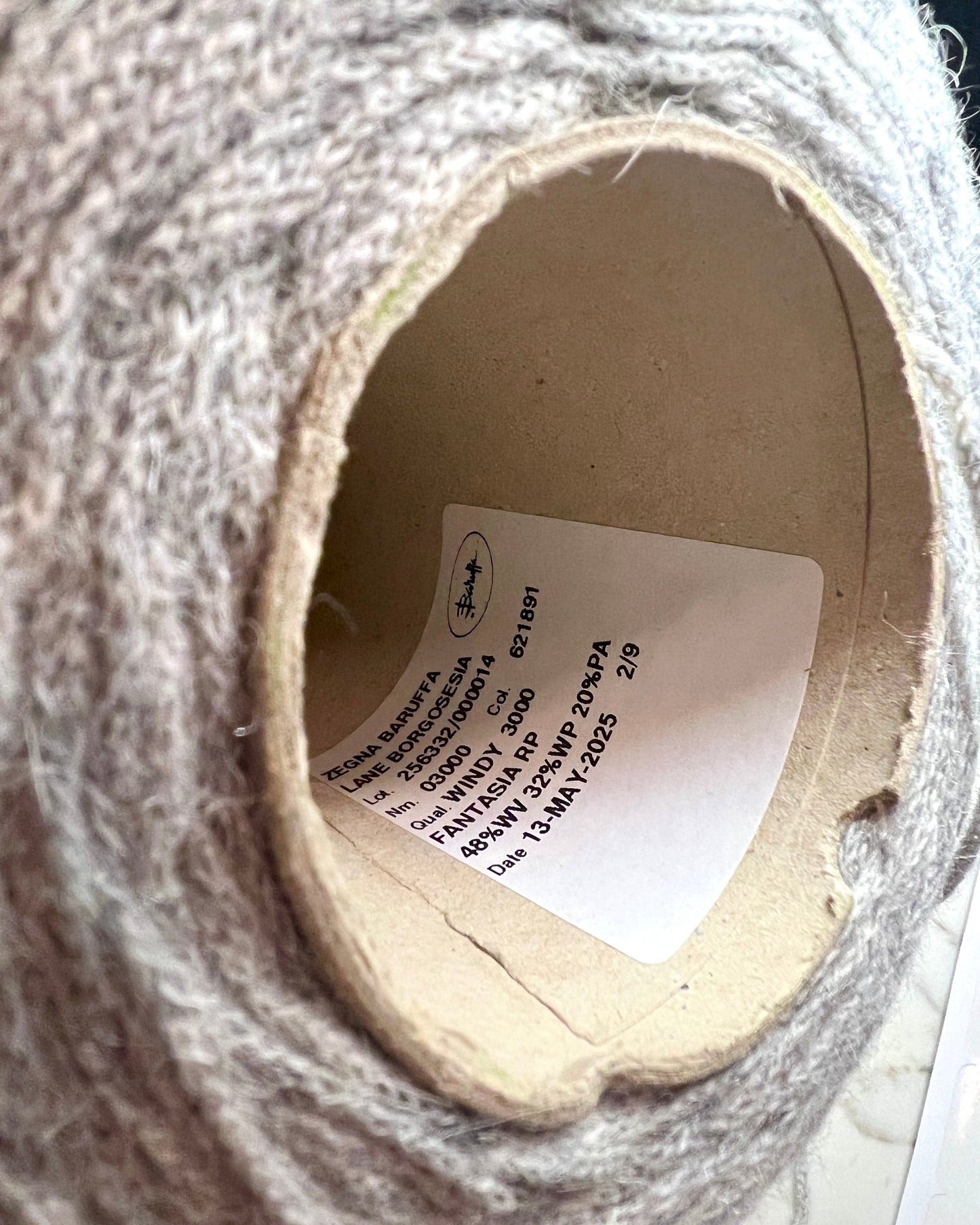 Close-up of a spool of gray yarn with a label inside