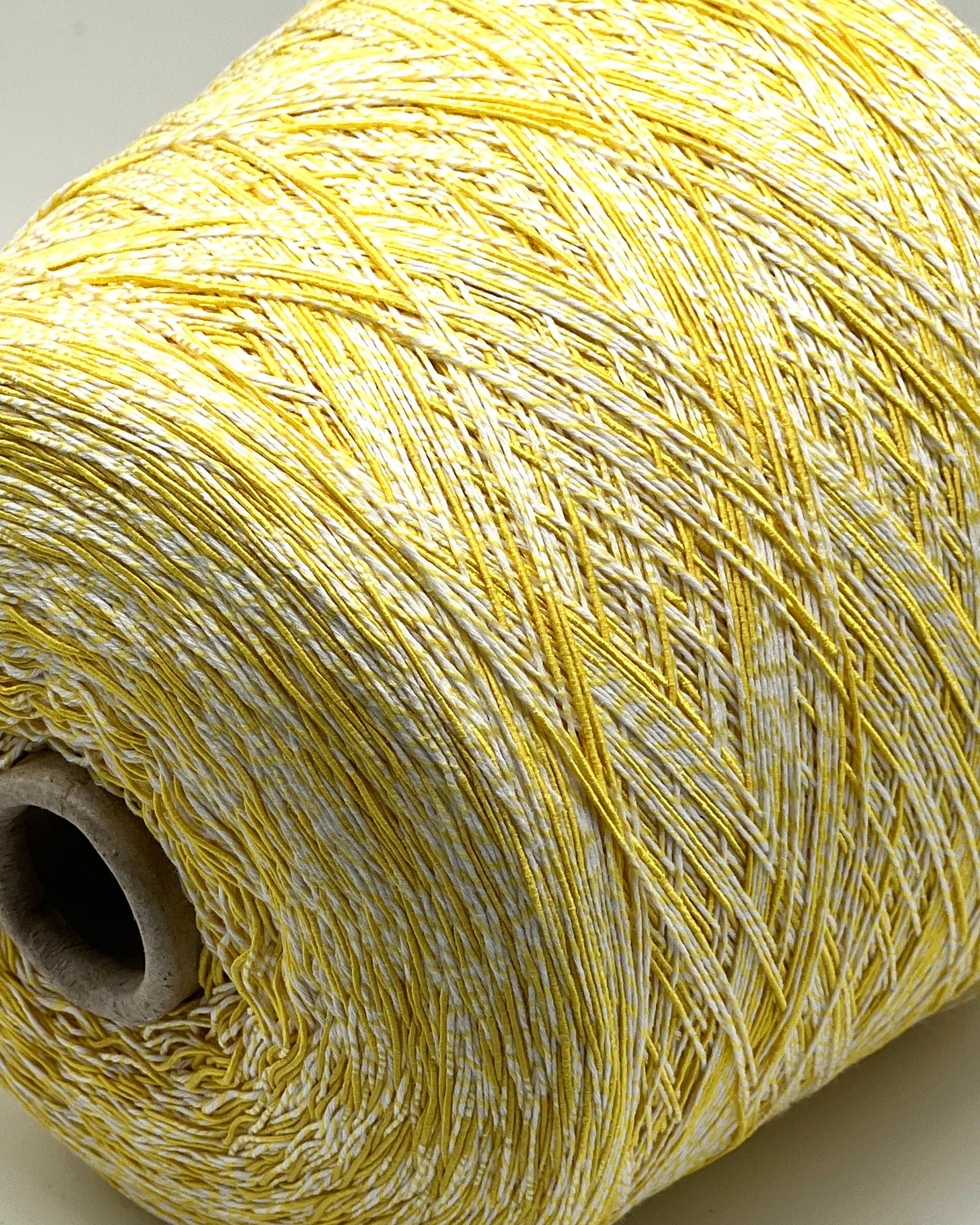 Close-up of a spool of yellow thread on a neutral background