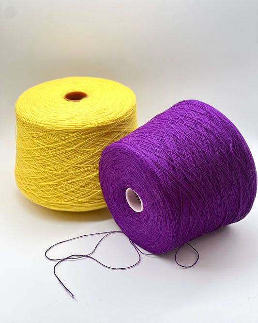 Two spools of yarn, one yellow and one purple, on a white background.