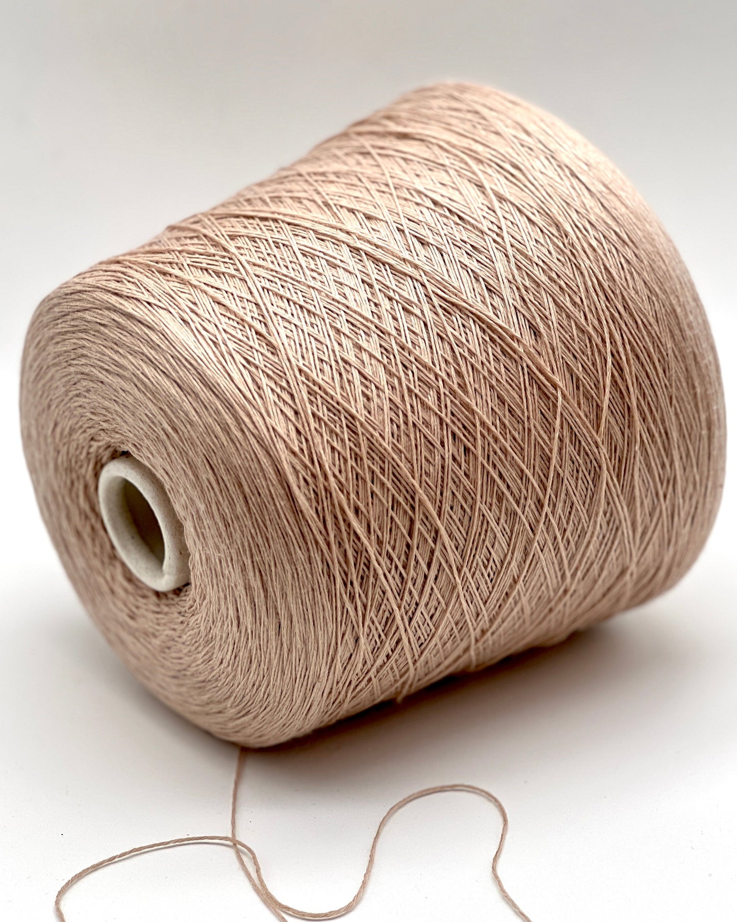 Spool of beige yarn on a white background