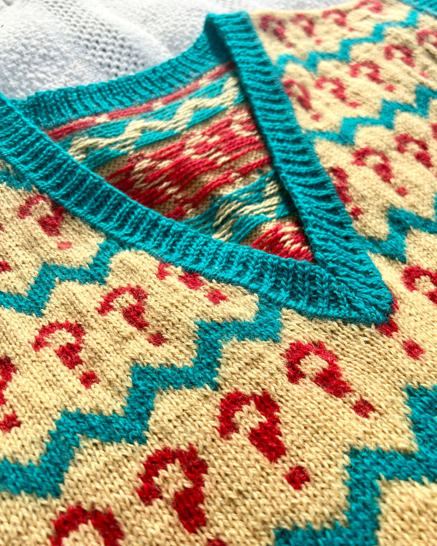 Close-up of a knitted garment with a colorful pattern featuring red and blue zigzag lines.