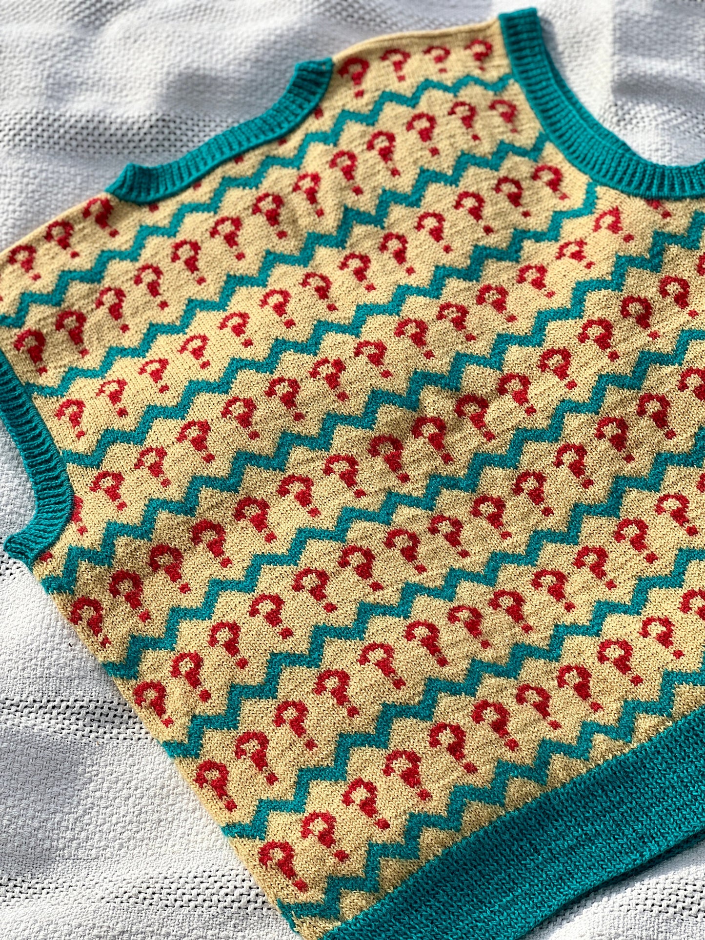 Knitted baby sweater with red and green pattern on a white background