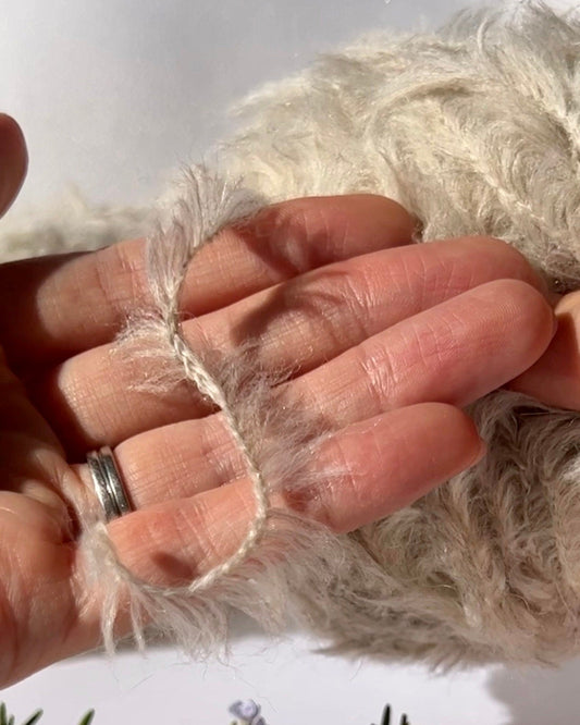 Close-up of a hand holding a piece of beige fabric with a blurred background