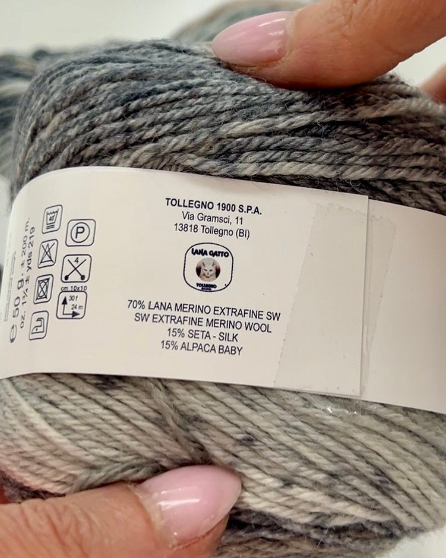 Yarn ball with a label held by a hand against a neutral background