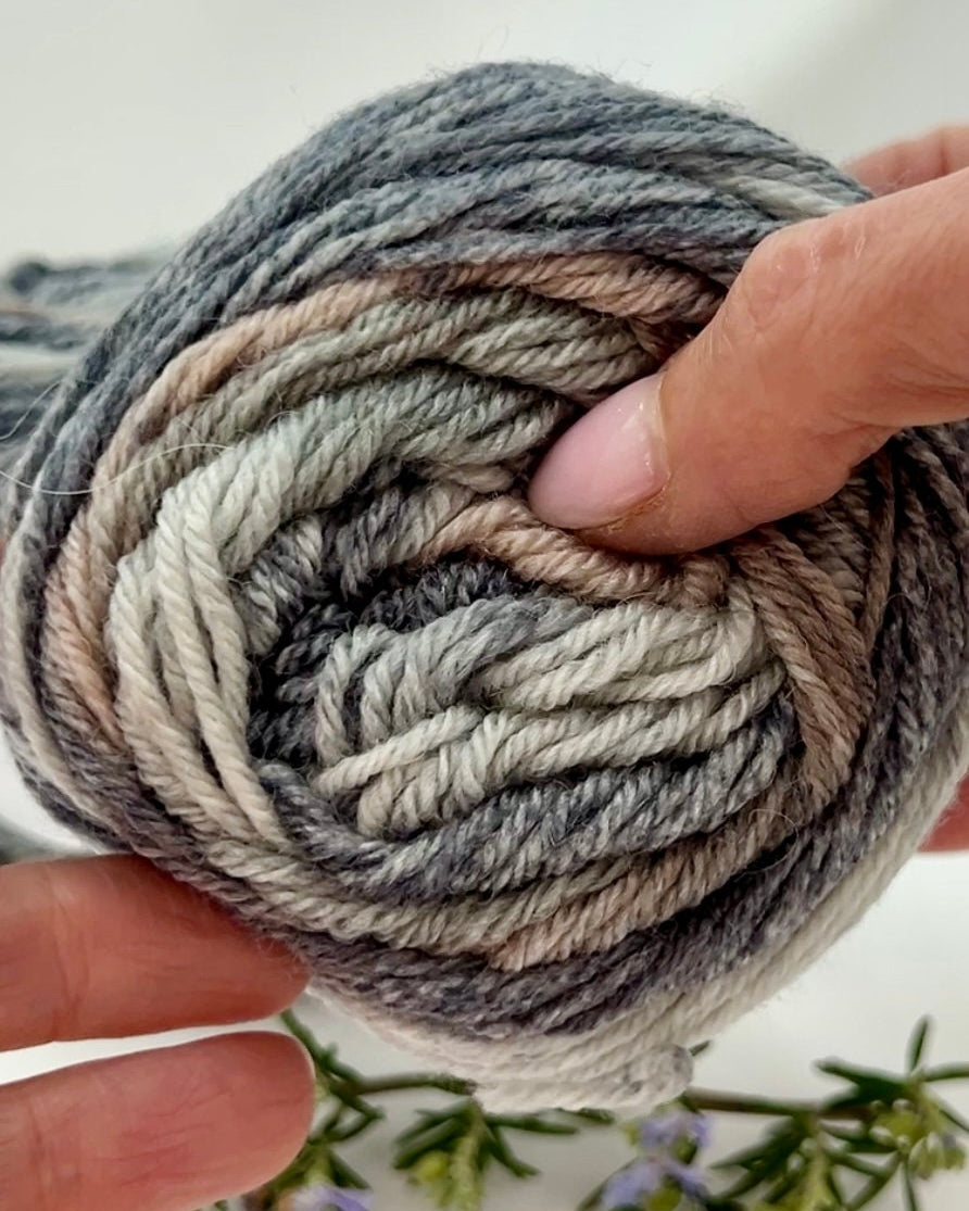 Hand holding a skein of multicolored yarn with a blurred background