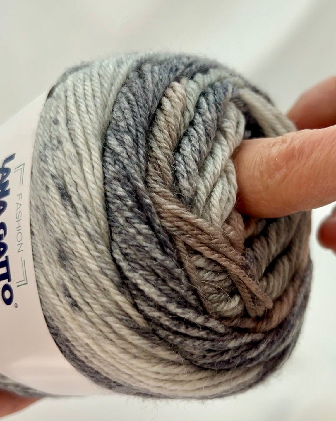 Ball of yarn with a hand holding it, branded 'Lana Grossa'.