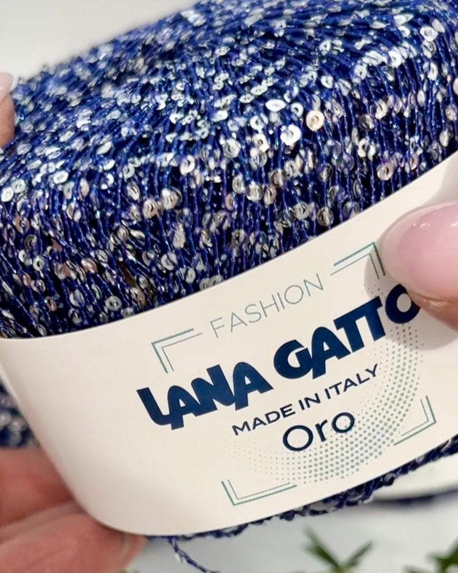 Blue and silver glitter yarn with 'Lana Gatto' label held by a hand