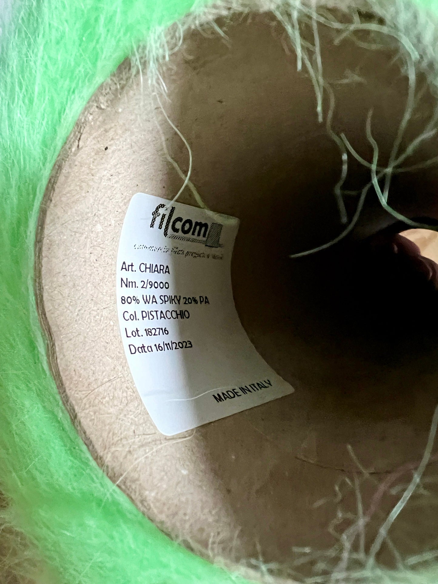 Spool of yarn with a Filcom label on a green background