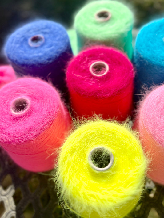 Colorful spools of yarn in various bright colors on a textured surface.