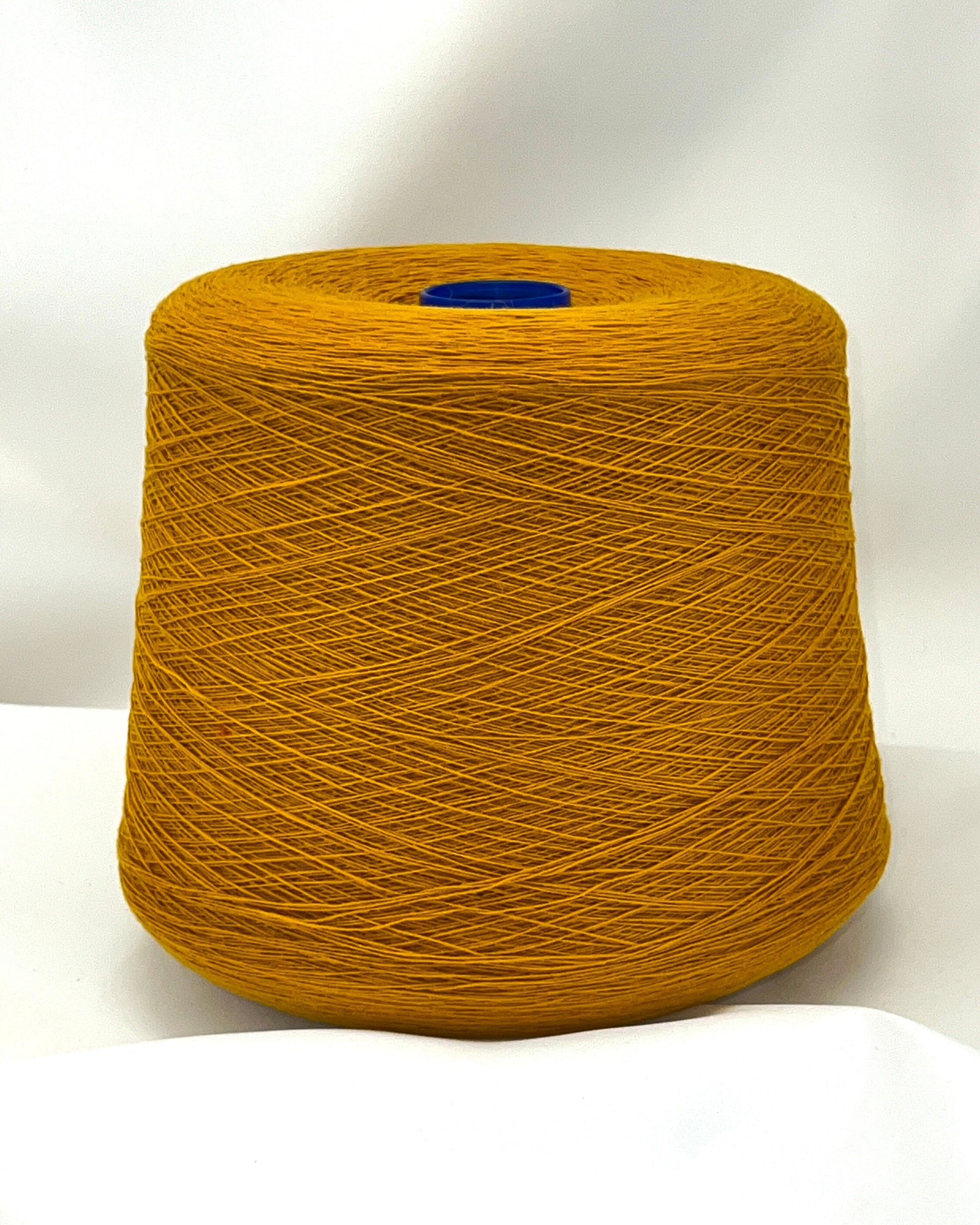 Large spool of mustard yellow yarn on a white background