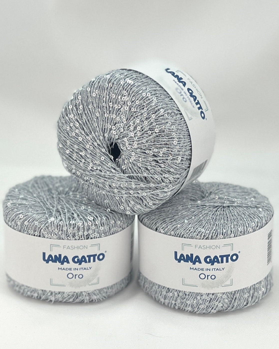 Three skeins of Lana Gatto yarn on a white background