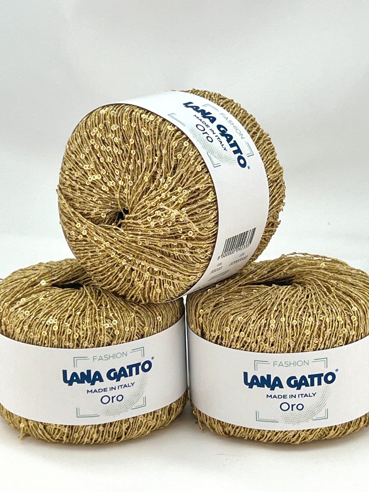 Three skeins of gold yarn with 'Lana Gatto' labels on a white background