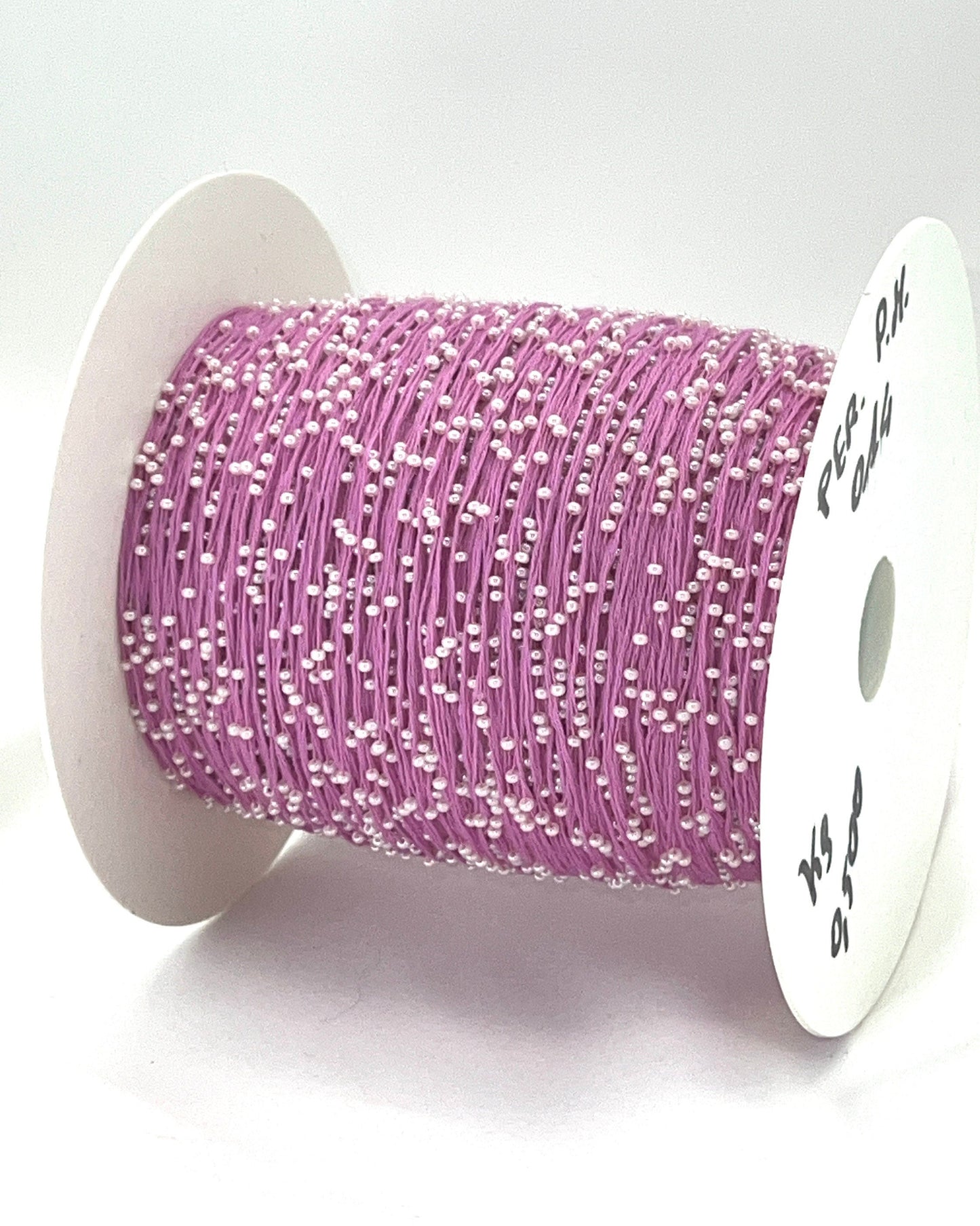 Spool of pink thread with white beads on a white background
