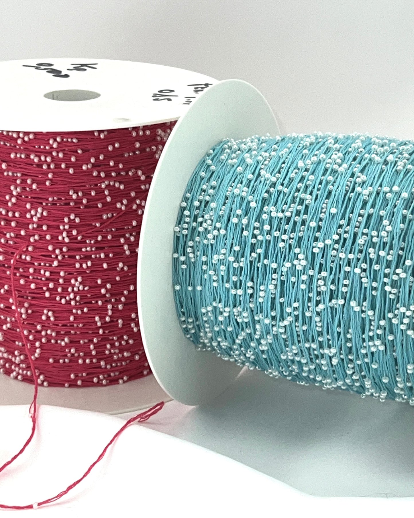 Two spools of thread, one red and one blue, on a white background.