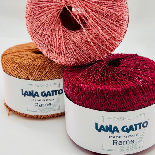 Two skeins of Lana Gatto yarn, one pink and one red, on a white background.