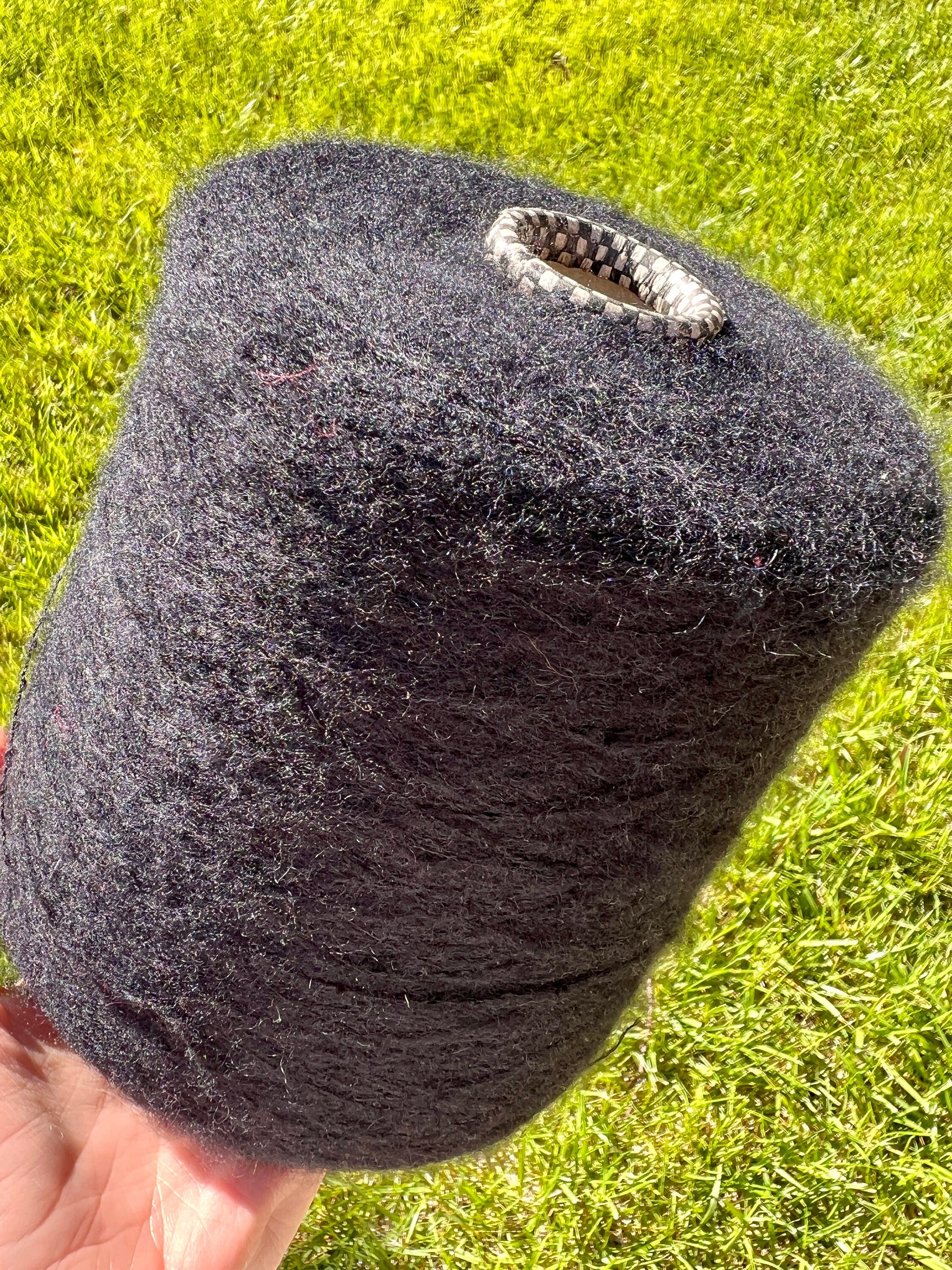 Black cylindrical object with a textured surface held against a grassy background