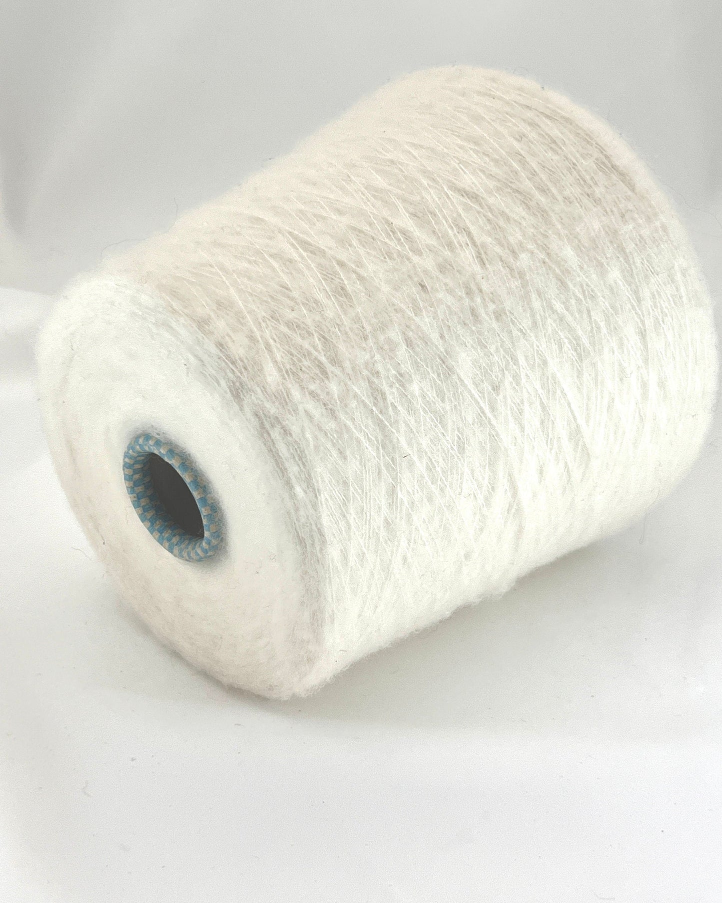 Spool of white yarn on a light gray background