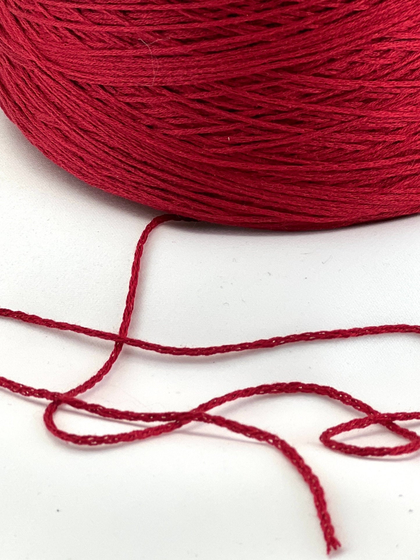 Red yarn spool with a single strand on a white background