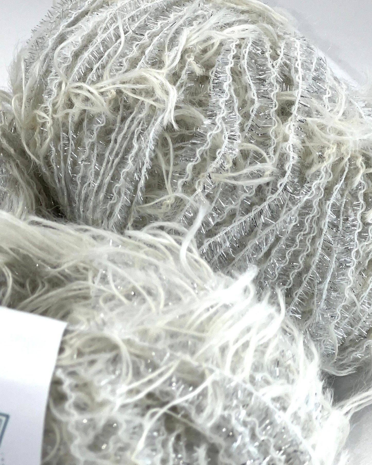 Close-up of a ball of white yarn with a visible brand label.