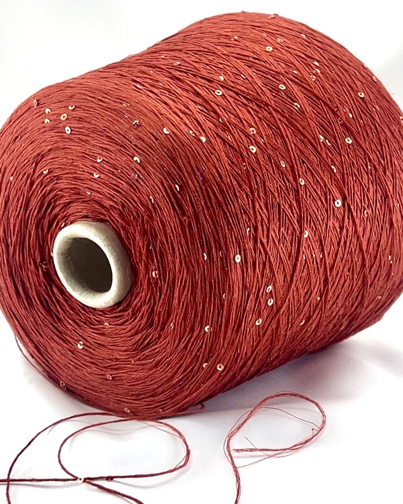 Red spool of thread with a small amount of thread unwound on a white background
