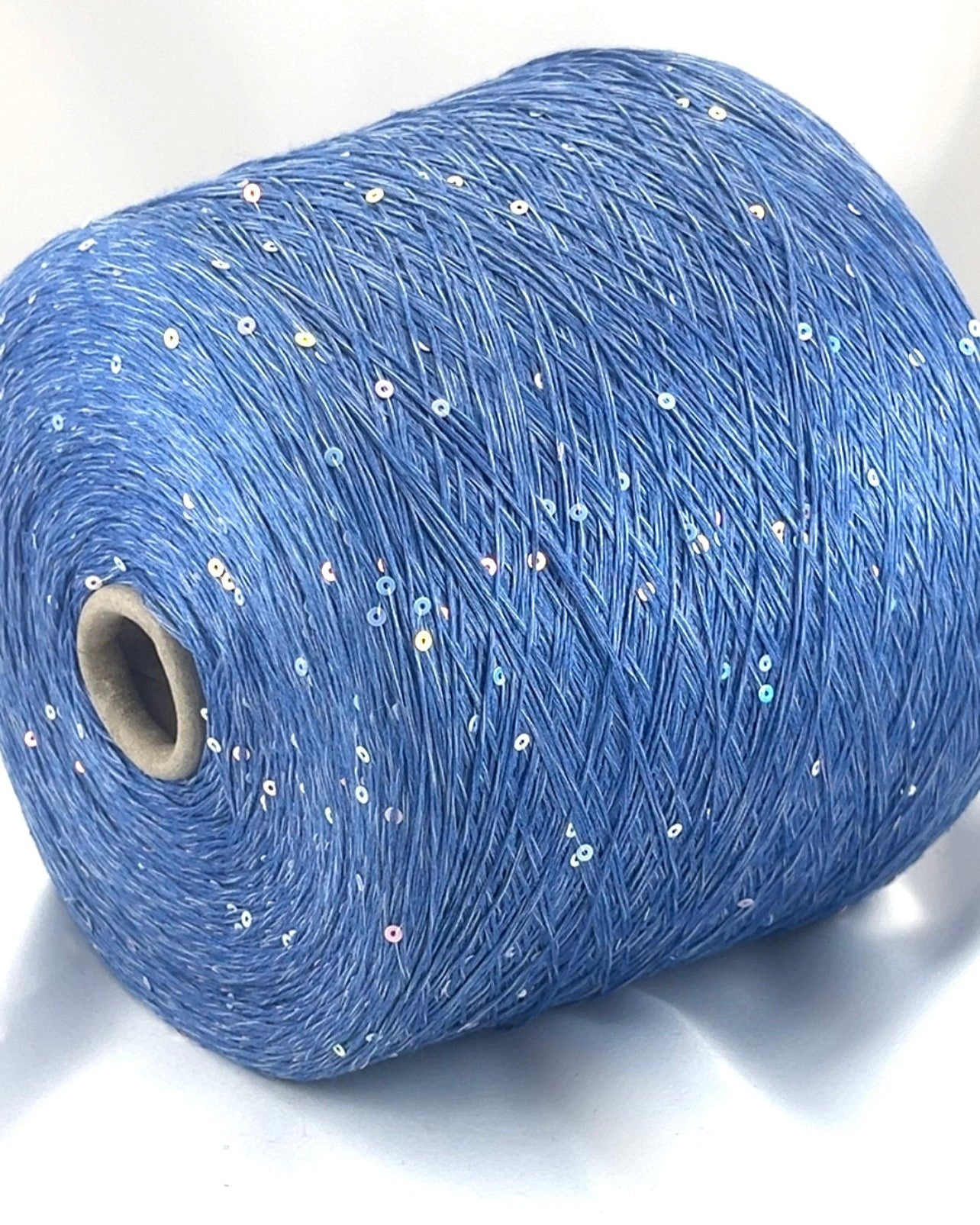 Blue yarn roll with glitter on a white background