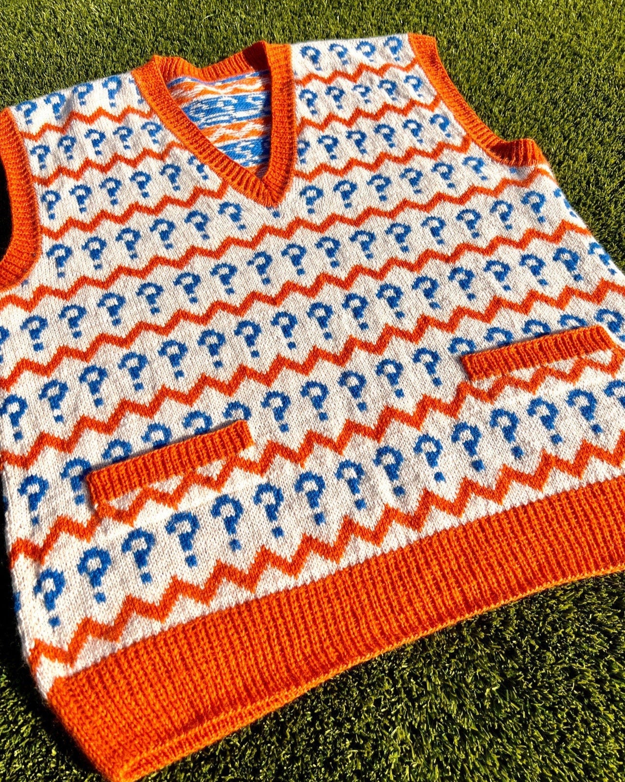 Knitted vest with question mark pattern on a grass background