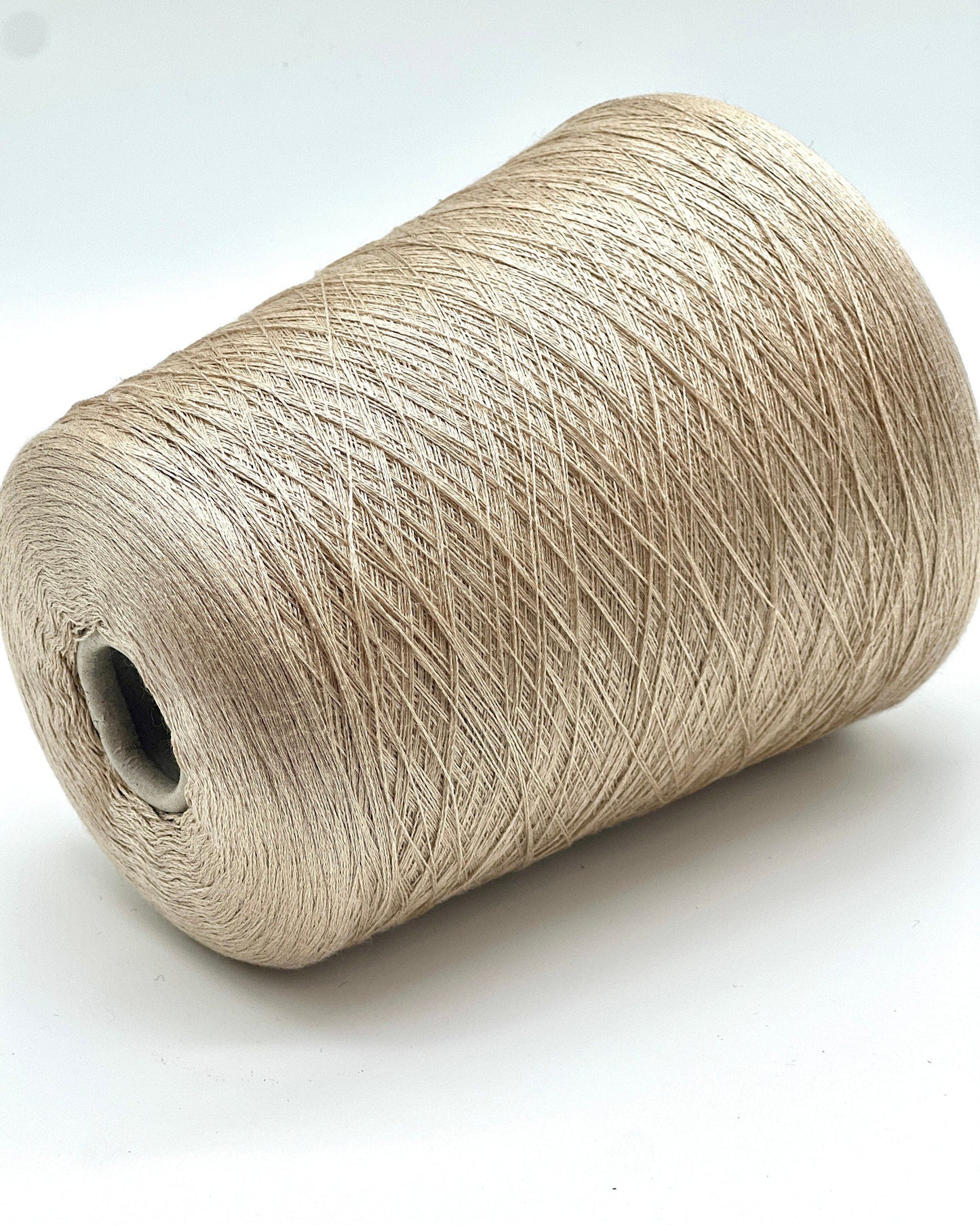 Spool of beige yarn on a white background