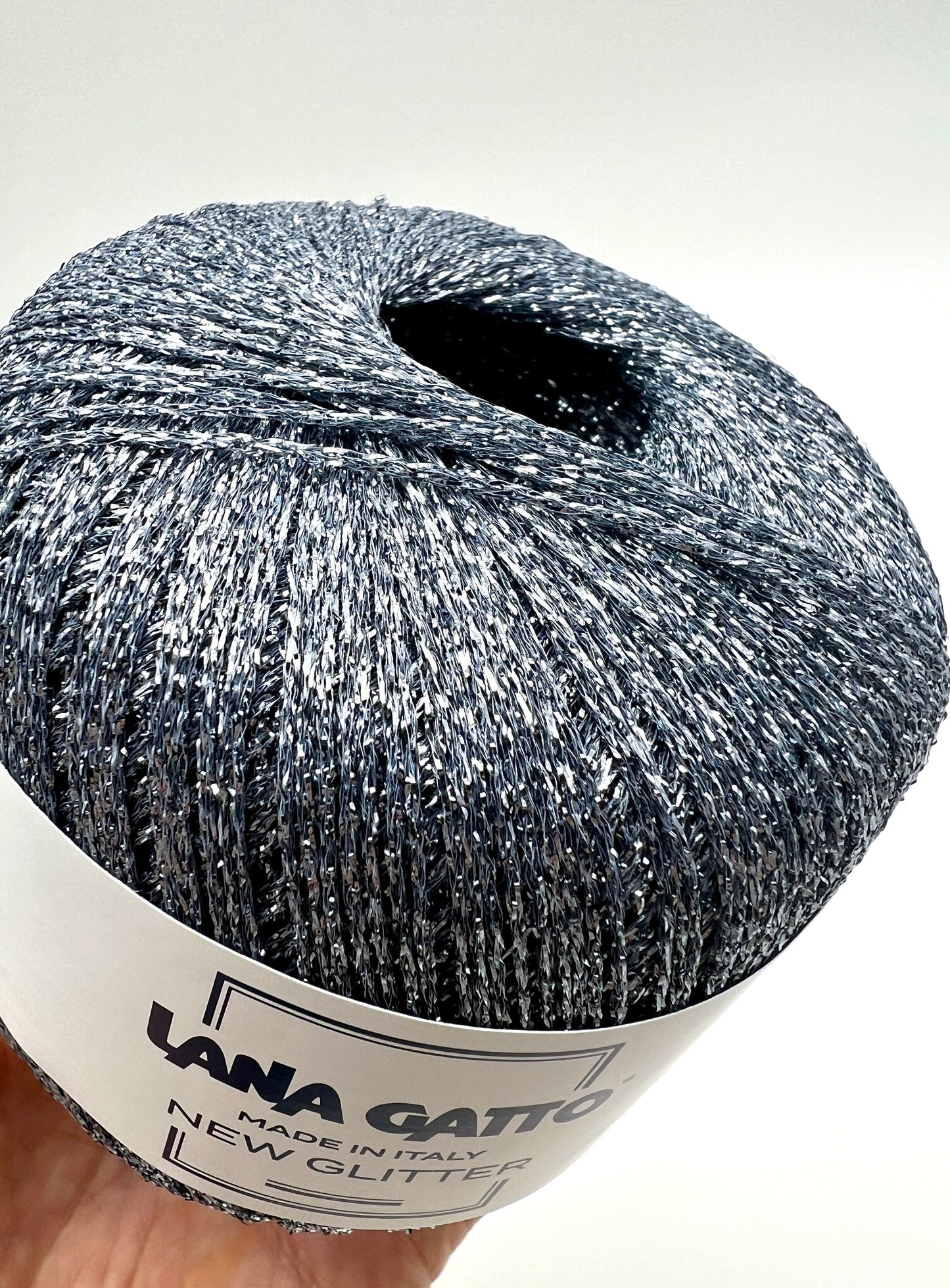 Ball of yarn with glittery texture and 'Lana Grossa' label on a white background