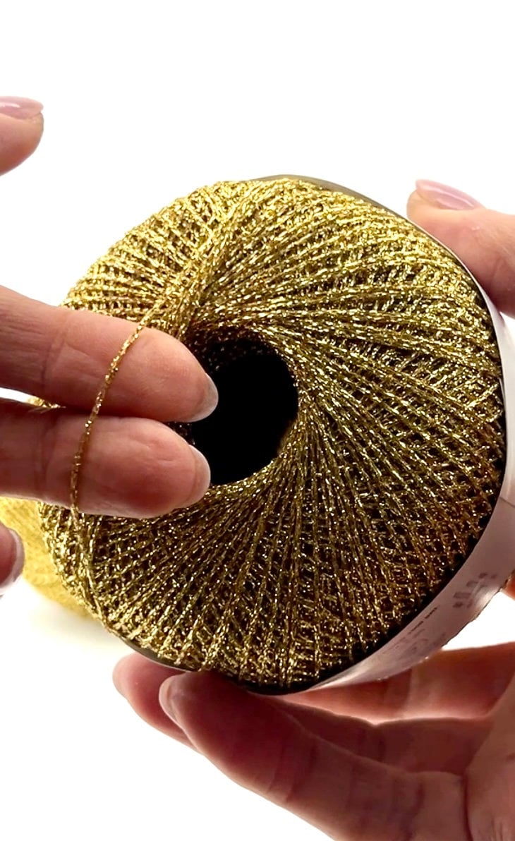Gold metallic ribbon roll held by hands against a white background