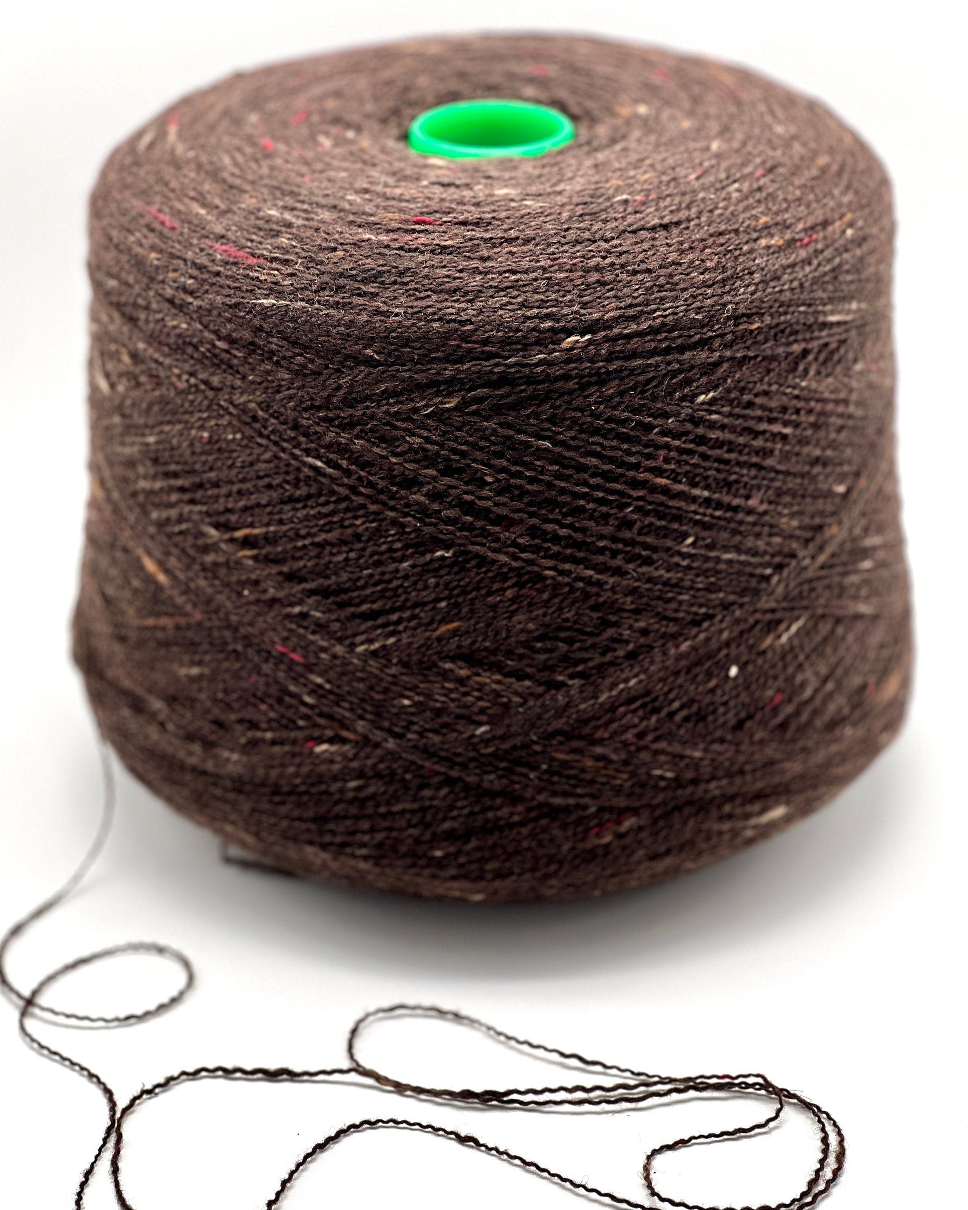 Brown yarn spool with a green knot on a white background