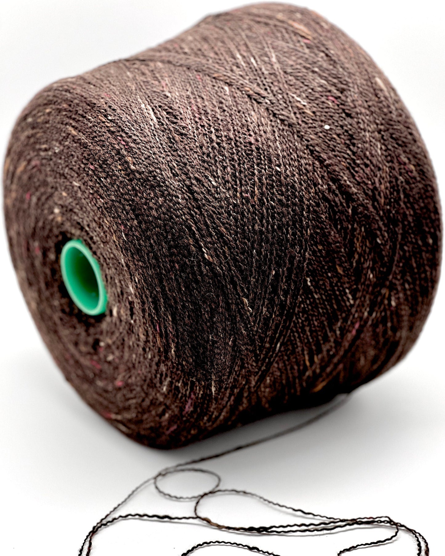 Brown spool of thread with a green core on a white background