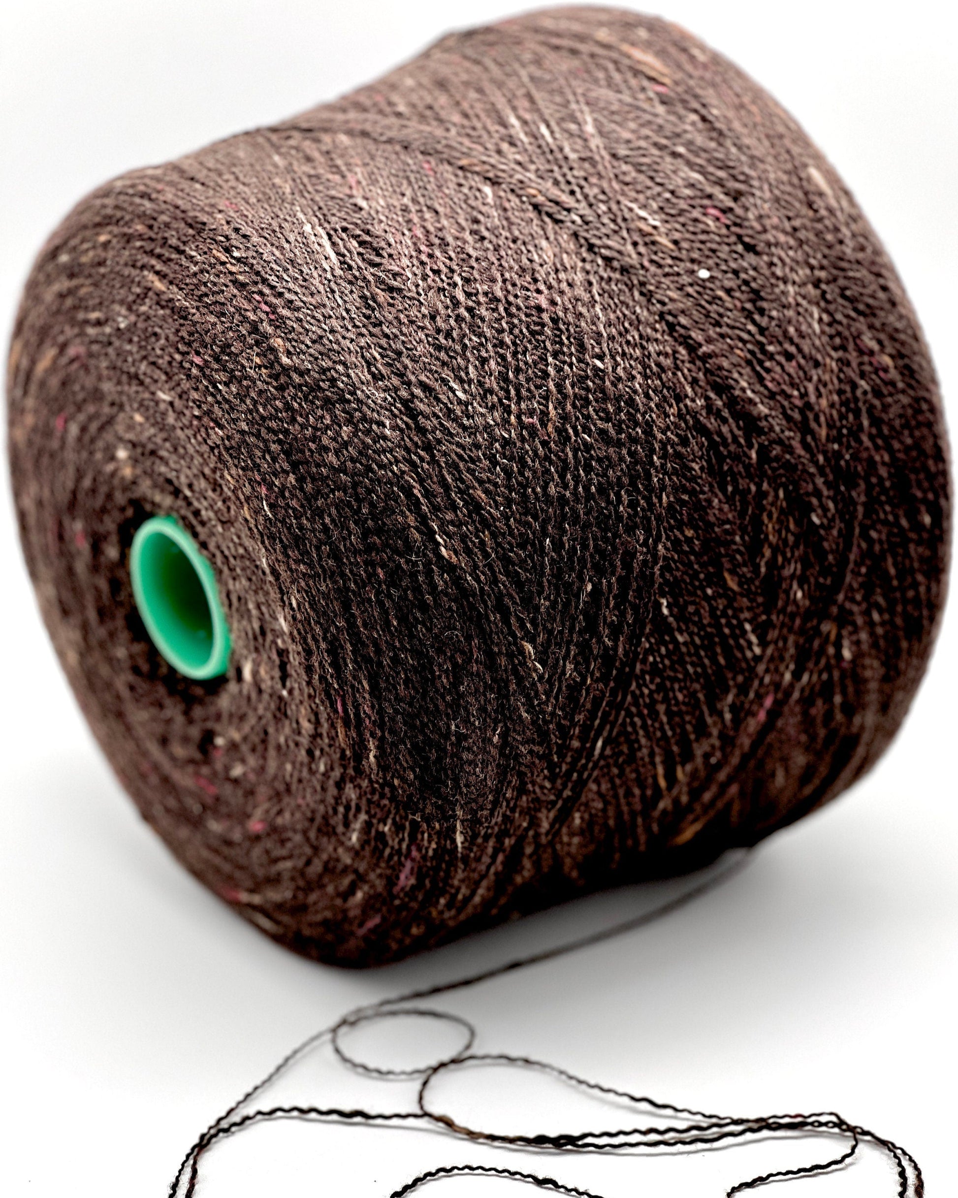 Brown spool of thread with a green core on a white background