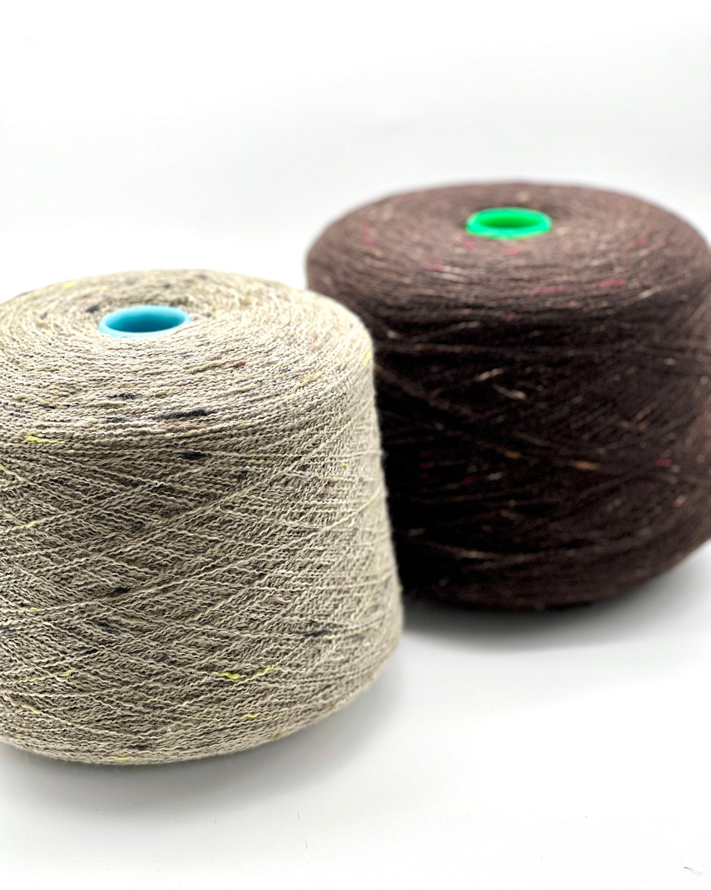 Two spools of yarn, one beige and one brown, on a white background.