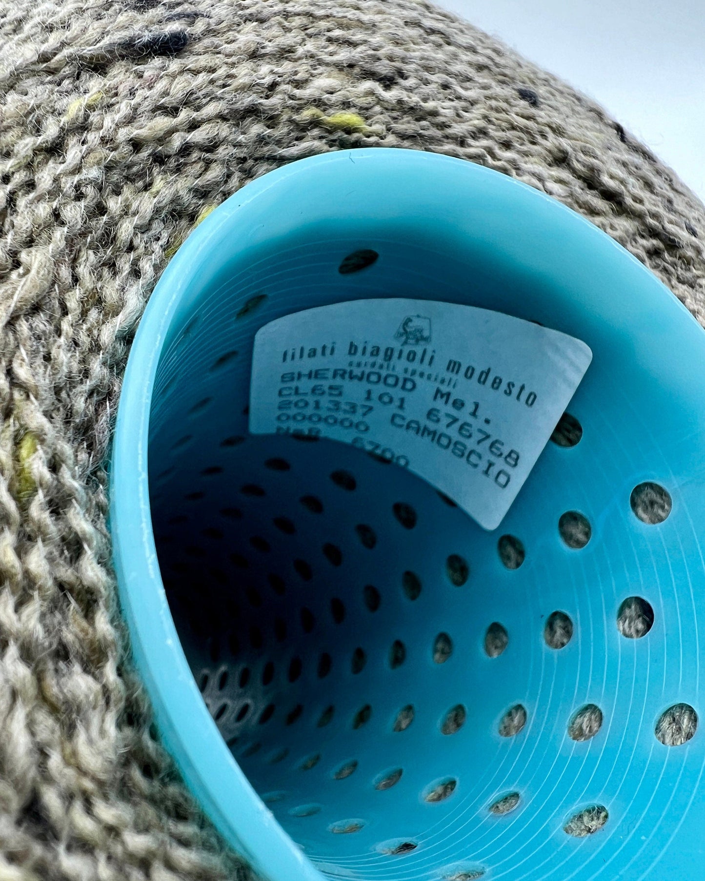Close-up of a blue plastic colander with a brand label on a textured surface.
