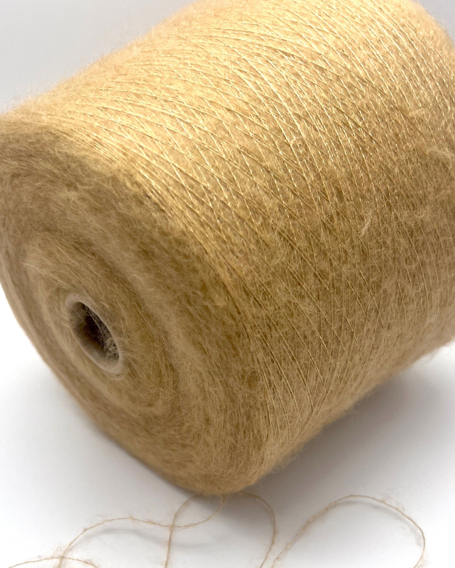 Close-up of a spool of beige yarn on a white background