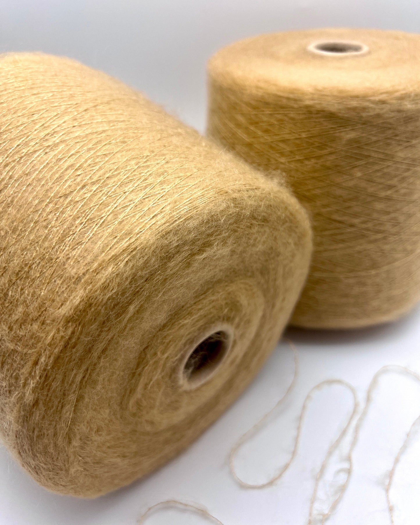 Two spools of beige yarn on a white background